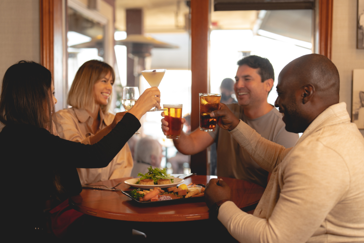 Four people cheers at a hightop table in the Fish Market lounge